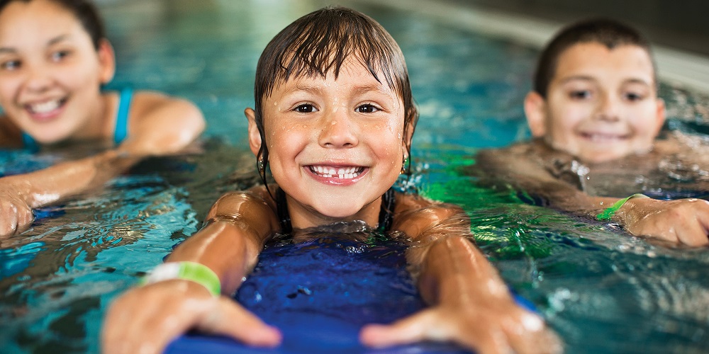 A school age kid splashing in the pool